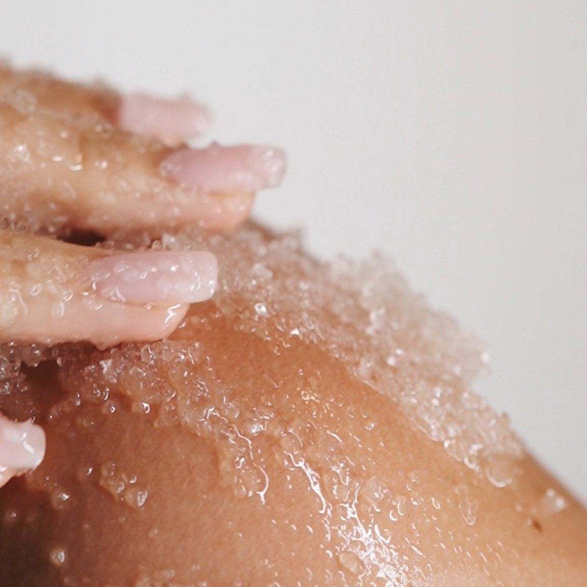Woman massaging Salt & Mud Dead Sea Salt Body Scrub crystals onto her shoulder