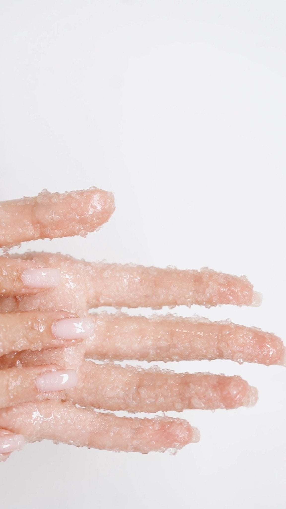 Close-up of fingers coated in Salt & Mūd Dead Sea Salt Body Scrub crystals