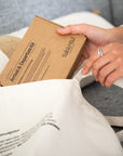 Person holding a cardboard box labeled 'Arrival & Diapering Kit' on a white surface.