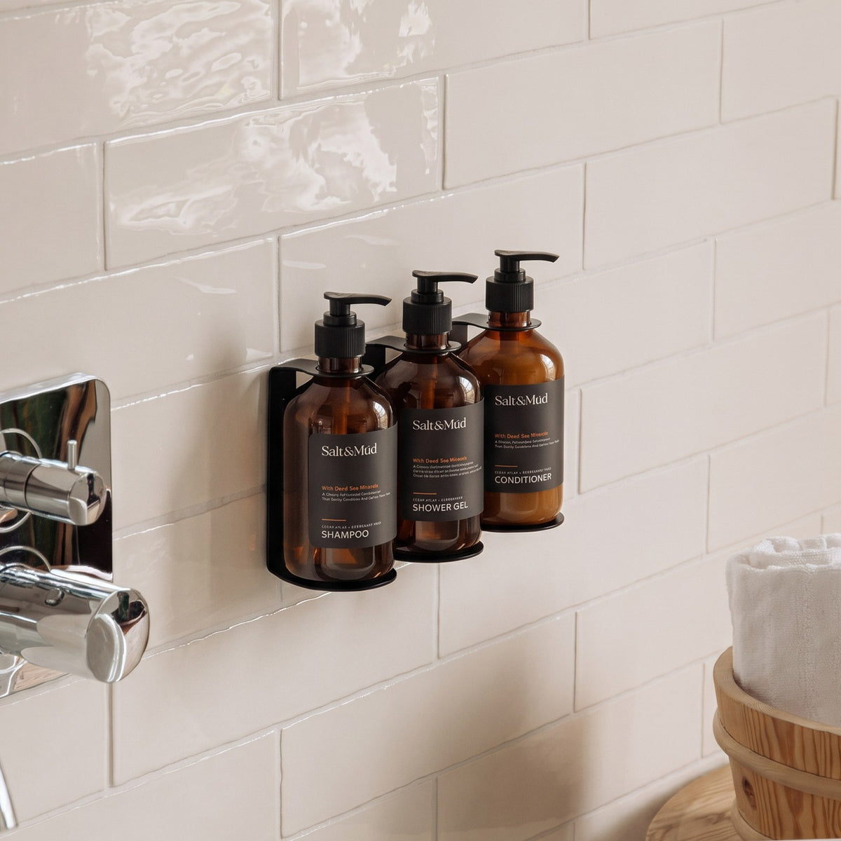 Salt & Mūd shampoo, shower gel and conditioner in wall brackets in a hotel shower